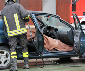 Fototapeta premium Zespół strażaków ciągnie rannego przez samochód mężczyznę po drodze a