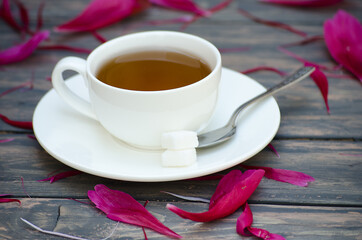 Hot tea and peony petals on dark