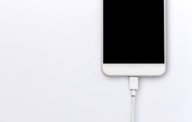 closeup smartphone and charger on white table. soft-focus and over light in the background