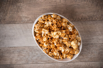 Caramel opcorn in bowl on the wooden table.