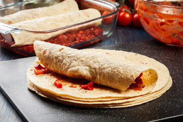 Preparation traditional mexican enchiladas with chicken meat, spicy tomato sauce and cheese