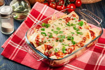 Traditional mexican enchiladas with chicken meat, spicy tomato sauce and cheese in heat resistant dish