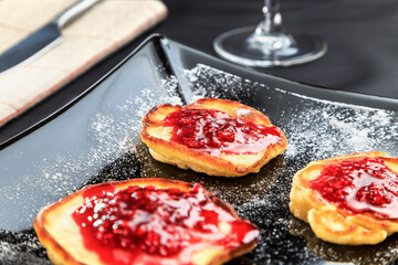 pancakes with raspberry jam on a beautiful black plate standing on the table