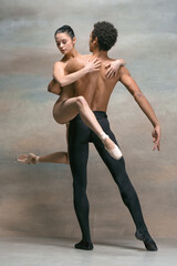 Couple of ballet dancers posing over gray background