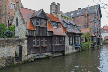 Fototapeta na wymiar Beautiful view on canal with old picturesque houses with brick and wooden facades in historic part of Bruges (Brugge), Belgium