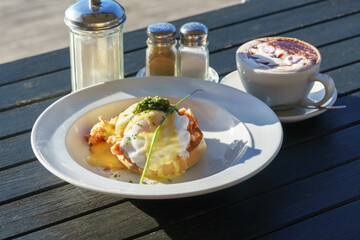 Delicious Eggs Benedict served on white plate on wooden table