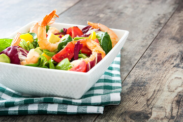 Shrimps salad with mango and avocado on wooden background

