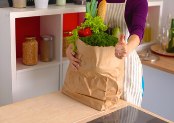 Healthy positive happy woman holding a paper shopping bag full of fruit and vegetables