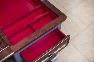 Self-made blue table with an open lid with cells for storage and a box of bright red color. Close-up.