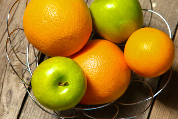 Apples and oranges on old wooden background