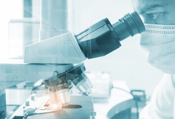 Scientist looking through a microscope for Medical test samples, Laboratory research concept.