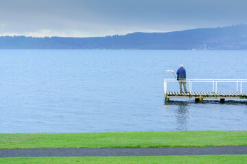 Old man standing on the bridge at Lake Taupo , South Island of New Zealand
