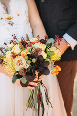 Autumn fashion wedding bouquet in hands of the bride and groom.