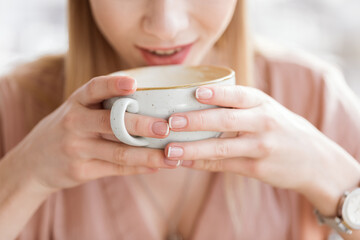 close up view of woman drinking coffee from big cup