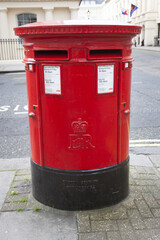 large double red letterbox on pavement in london