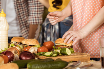 cropped shot of woman preparing hamburgers for friends on kitchen board