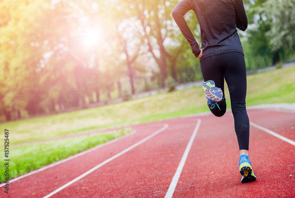 Poster Athletic woman running on track back view, healthy lifestyle