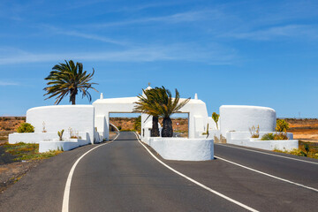 road with white entry gate and palm trees, Lanzarote Spain