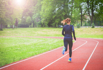 Athletic woman running on track back view, healthy lifestyle