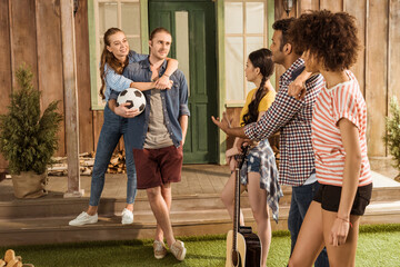 Obraz premium multiethnic friends with soccer ball and guitar, talking and spending time together