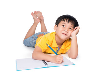 Schoolboy lying on a floor, looking up and writing in notebook.