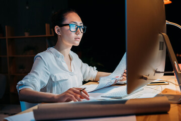 young concentrated asian businesswoman in eyeglasses working with documents and computer - Powered by Adobe