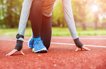 Athletic woman on running track getting ready to start