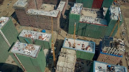 Aerial shot of big construction site. Rooftops of unfinished modern apartment buildings