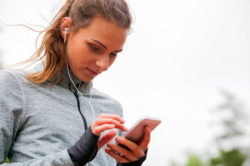 Athletic woman before start running setting up her smart phone app