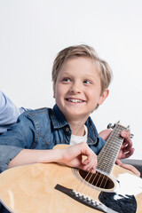 adorable caucasian boy practicing to play on guitar isolated on white