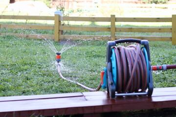 Sprinkler and reel with hose are in the garden.