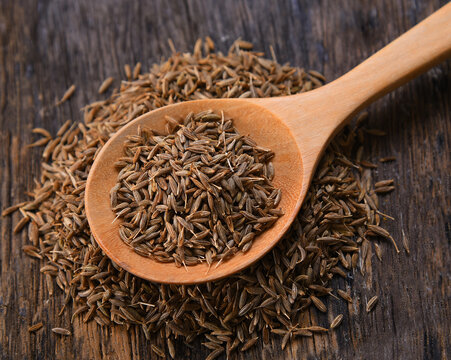 Cumin seeds in spoon wood on table background