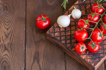 Fresh raw cherry tomatoes on a wooden board with pepper garlic. Wooden background. Close up and copy space. Overhead view.