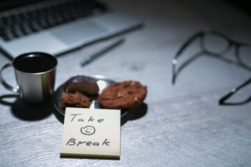 office working desk with laptop, pen and and glasses and coffee with cookie and stickers or memo notes