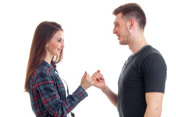 young girl and Guy stare at each other smiling and holding little fingers isolated on a white background