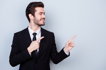 Happy smiling with perfect hairstyle man dressed in suit pointing on copyspace and looking away