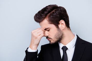 Side view portrait of sad man in formal clothes touching his nose bridge because of having headache