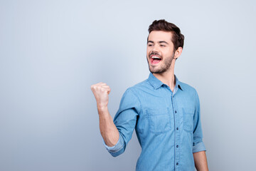 Winner! Young handsome man is celebrating victory. He is raising up fist and screaming