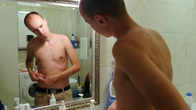 Young man checking his look in front mirror in bathroom. thin guy looking at the mirror.