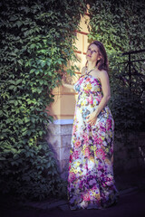 Pregnant woman on the corner of a house crooked with ivy