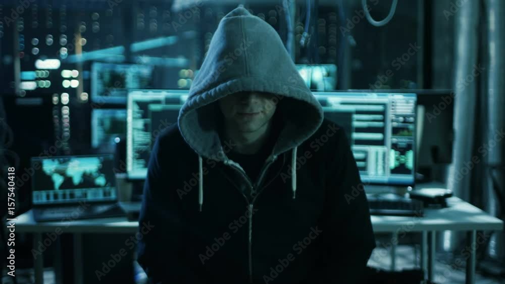 Poster dangerous internationally wanted hacker speaks into the camera. in the background his operating room