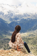 Woman traveller sitting on edge and enjoying mountain view