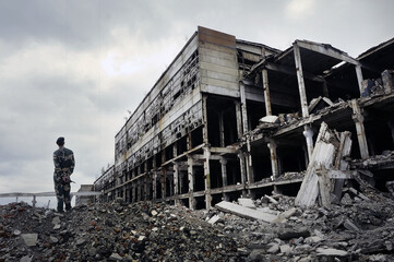 Soldier in military uniform stands on the ruins