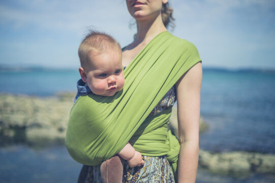 Young mother on coast with baby in sling