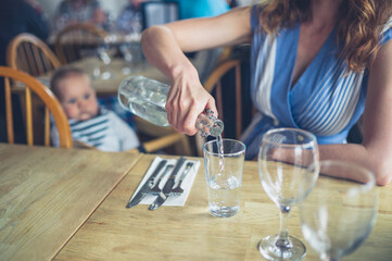 Woman pouring water at table with baby