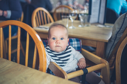 Cute little baby sitting at table in restaurant