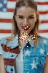 hipster girl in american patriotic outfit holding sparkler with us flag on background, 4th july - Independence Day celebration