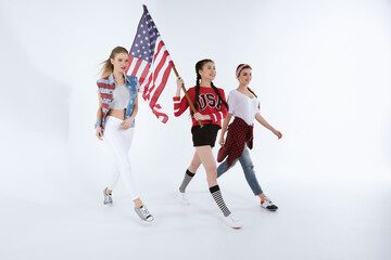 Fototapeta na wymiar multiethnic girls walking with american flag and celebrating 4th july isolated on white