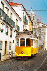 Famous vintage yellow 28 tram on street of Alfama, the oldest district of the Old Town, Lisbon, Portugal