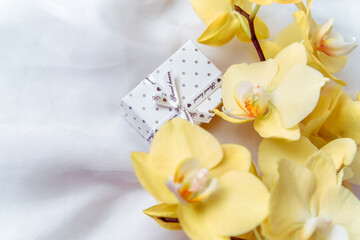 Naklejka na ściany i meble Gift box on a background of yellow orchids 